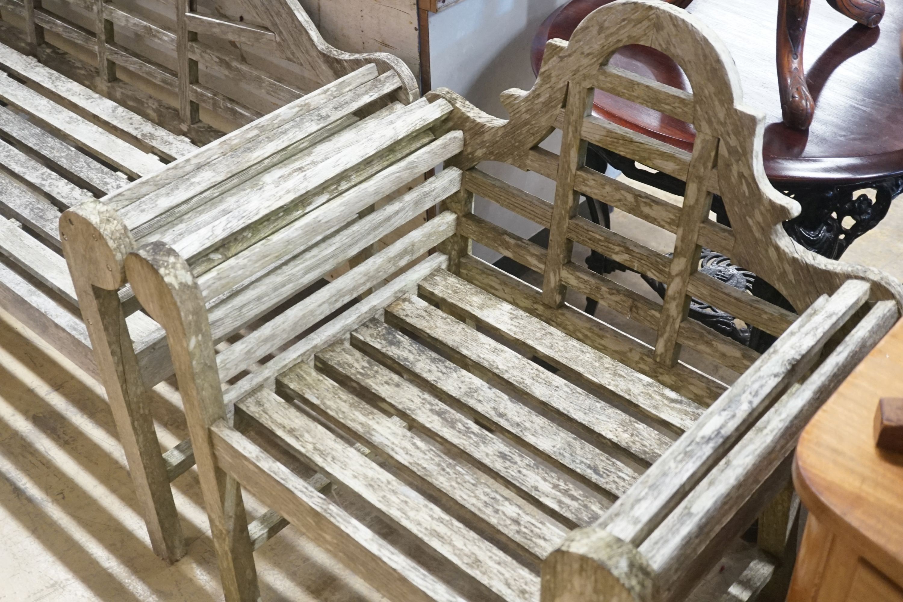 A Lutyens style weathered teak garden bench, width 164cm depth 56cm height 106cm, and two chairs